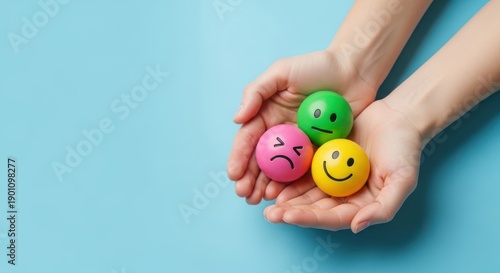 Hands holding three smiley balls with different emotions on blue background