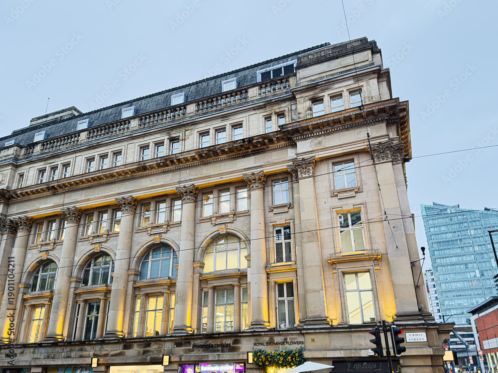 Fototapeta premium Historic city building in Manchester with ornate columns and busy Cross street life by shopfronts