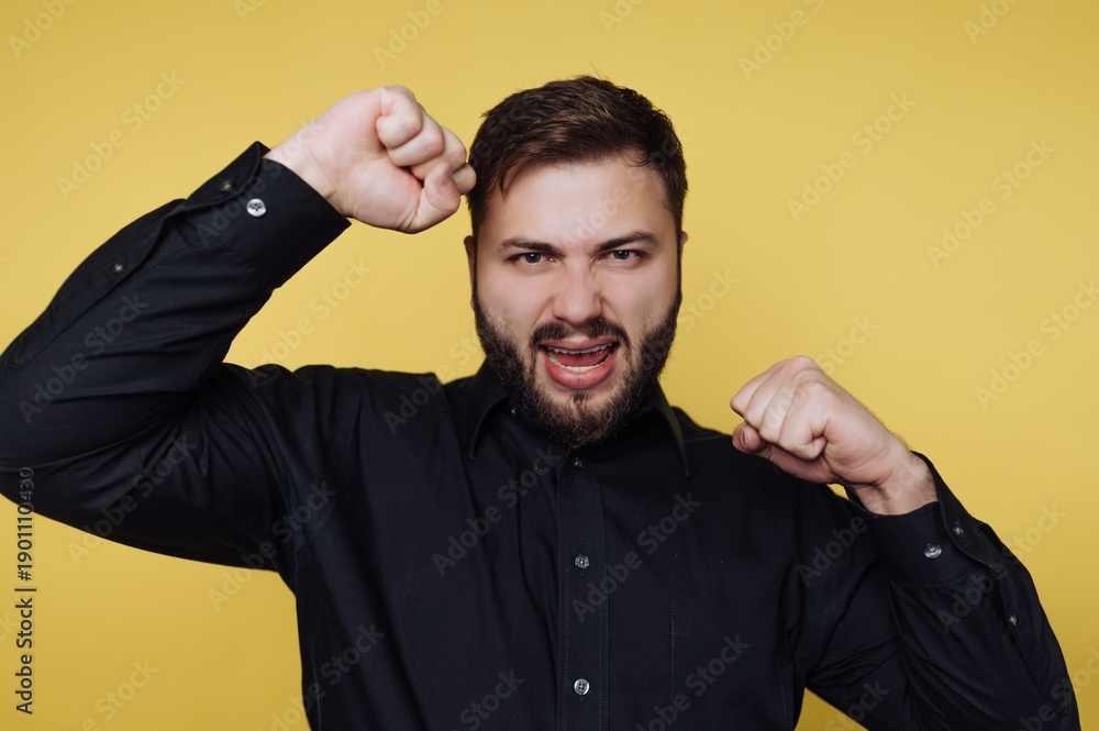 Fototapeta premium Man showing strong emotions and performance in front of a bright yellow background during a lively moment