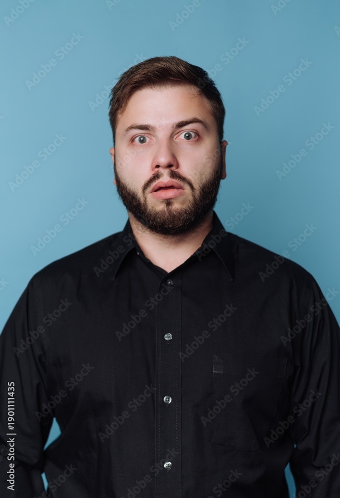 Obraz premium Man with surprise expression stands against blue background