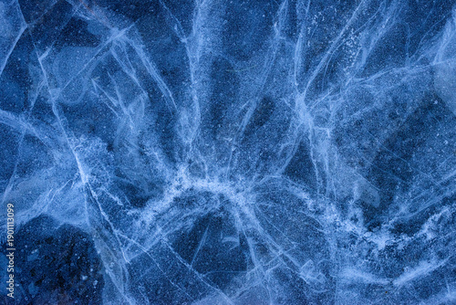 Abstract blue ice texture with natural cracks and frozen patterns on a winter lake surface. Cold icy background suitable for banners, wallpapers, and seasonal design projects.