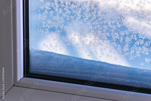 Frost and snow crystals on window glass in winter.  Frost on the window. Close-up of icy patterns and frozen texture on window pane, cold weather and seasonal background.