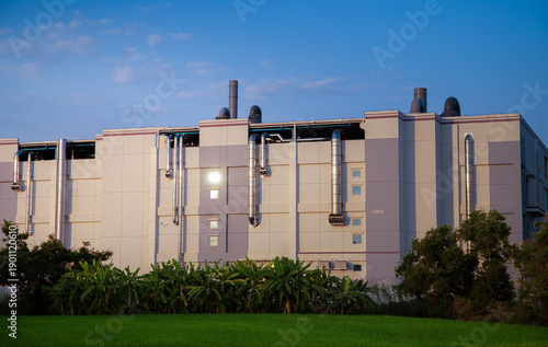 Modern factory architecture featuring shiny metal air conditioning and ventilation pipes.Industrial ventilation system on the exterior wall of a modern factory building