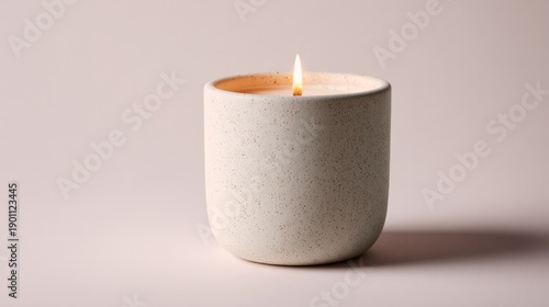 A white candle in a white ceramic container
