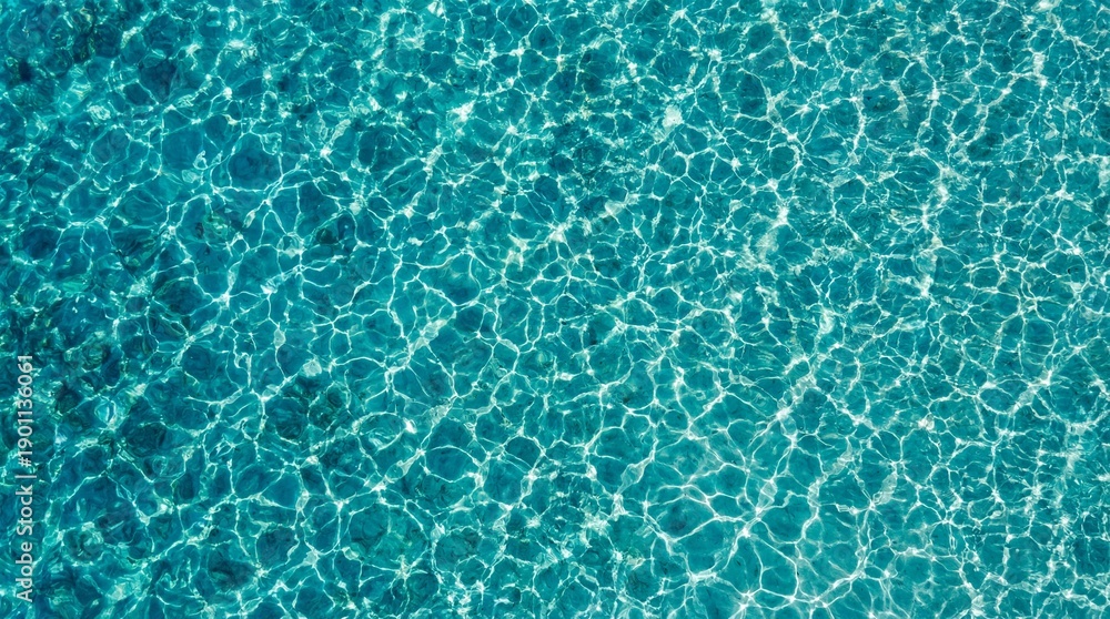 Obraz premium Aerial view of clear turquoise ocean water with shimmering sunlight reflections and ripple patterns, abstract water surface texture