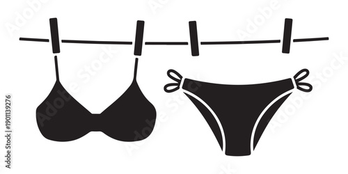 Black bikini bra and panties hanging on clothesline with clothespins isolated on white background