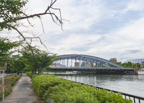 川沿いの遊歩道と都会にかかる大きなアーチ橋