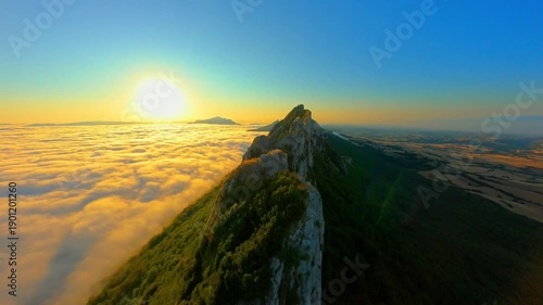 Majestic sunset over sharp mountain ridge above sea o clouds