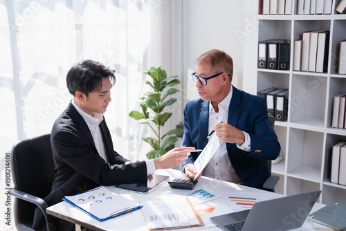 Bilde på lerret Two businessmen collaborate in a modern office, reviewing financial reports, cha