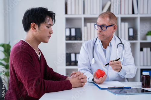 Canvas Print Doctor in white coat and stethoscope discussing heart health with a young male p