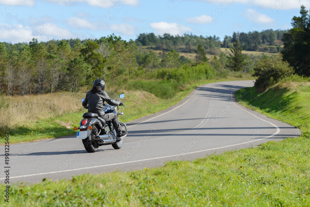Obraz premium biker on a custom classic motorcycle rides down the road, road traffic