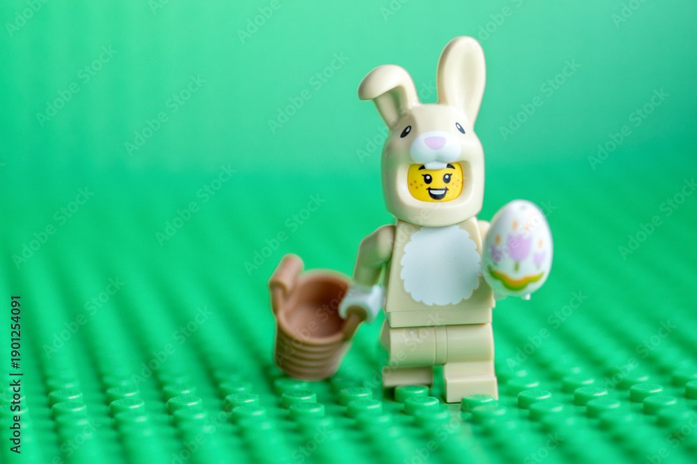 Naklejka premium Lego Easter Bunny with Egg and Basket on Green Baseplate. Easter holiday concept.