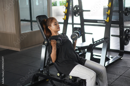 Focused woman performing seated incline dumbbell curls