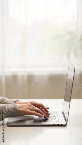 Woman's hands typing on a laptop at home, working on email, business report, data entry, research, and remote communication for company tasks.