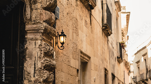 Tableau sur toile Old town in Italy, a shining lantern by an old wooden door,  characteristic sand