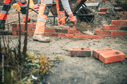 Bricklayers laying bricks building a wall building a house wearing hi vis and PPE 