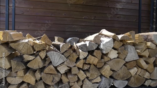 Stacked Firewood in a Wooden Shed With a Garden House in the Background