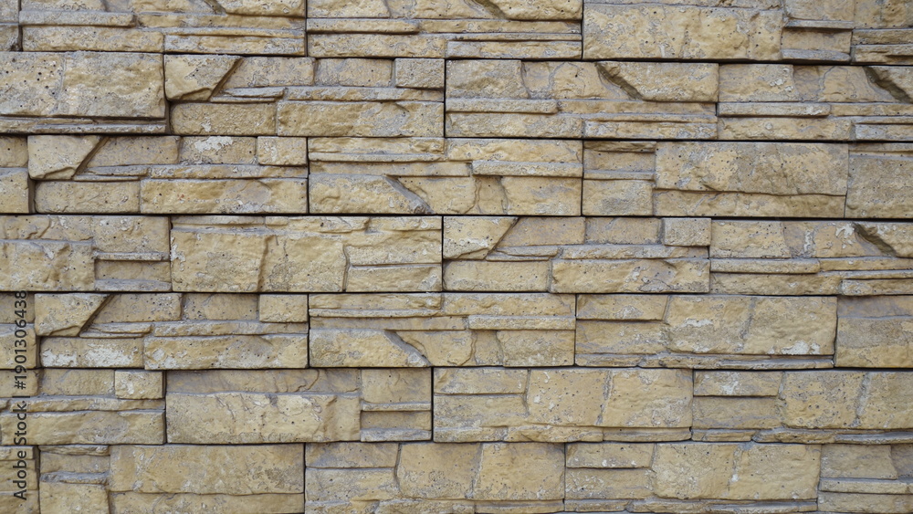 Obraz premium Textured beige stone wall with stacked pattern.