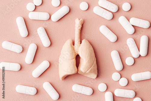 Tableau sur toile Human lungs model surrounded by white pills on pink background