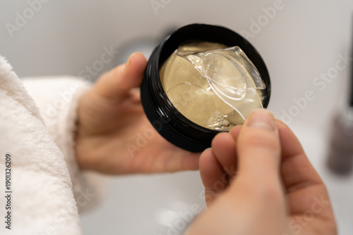 Cuadro en lienzo Womans hand takes golden hydrogel eye patch from jar