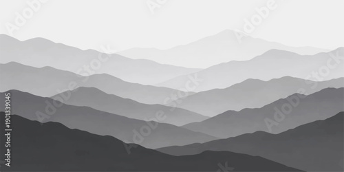 A misty blue mountain range silhouette unfolds under a hazy morning sky as fog settles over the peaks and forest valleys during a serene sunrise landscape view