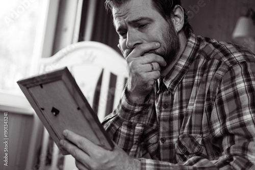 Photos Adult man looks at old photo of his parents and feels sad