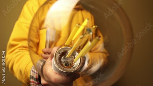 Person in a yellow hoodie holding a large vintage-style LED filament light bulb. Concept of idea, creativity, and energy