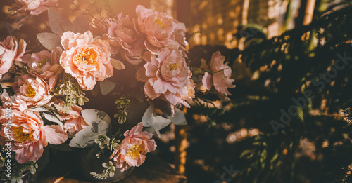 Soft pink flower bouquet with green leaves in warm sunlight creating peaceful and cozy atmosphere in room