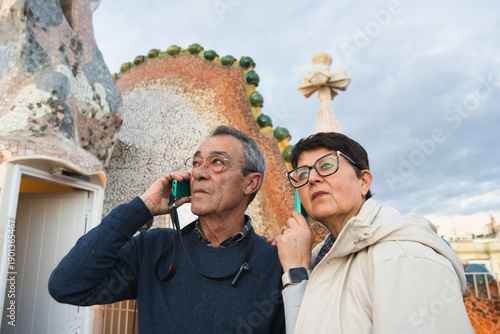 Картината върху платно Senior tourist couple using smartphones for communication or navigation, standin