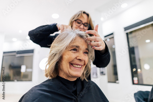 Schilderij op canvas Senior woman smiling while getting a haircut