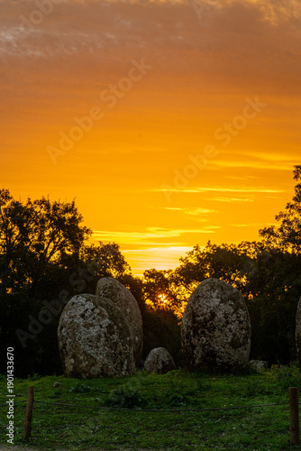 Sunrise at the Cromeleque dos Almendres near Évora, Alentejo, Portugal. An ancient Neolithic stone circle, one of the largest megalithic monuments in Europe, bathed in soft morning light.