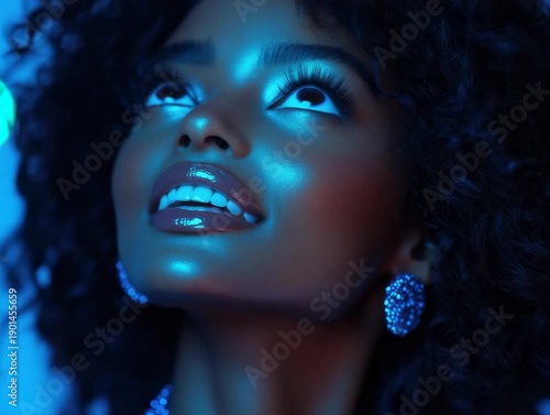 Wallpaper Mural Smiling woman looks up with shiny skin and glowing earrings under blue lights at a celebration in the evening Torontodigital.ca
