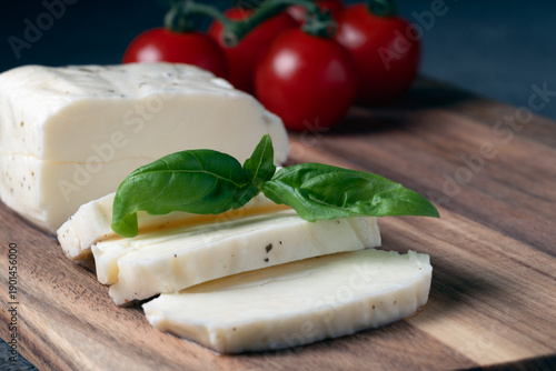 Close up of halloumi cheese slices with fresh basil and tomatoes in the background