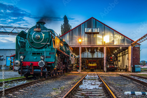three steam locomotives with one railcar resting overnight in the depot