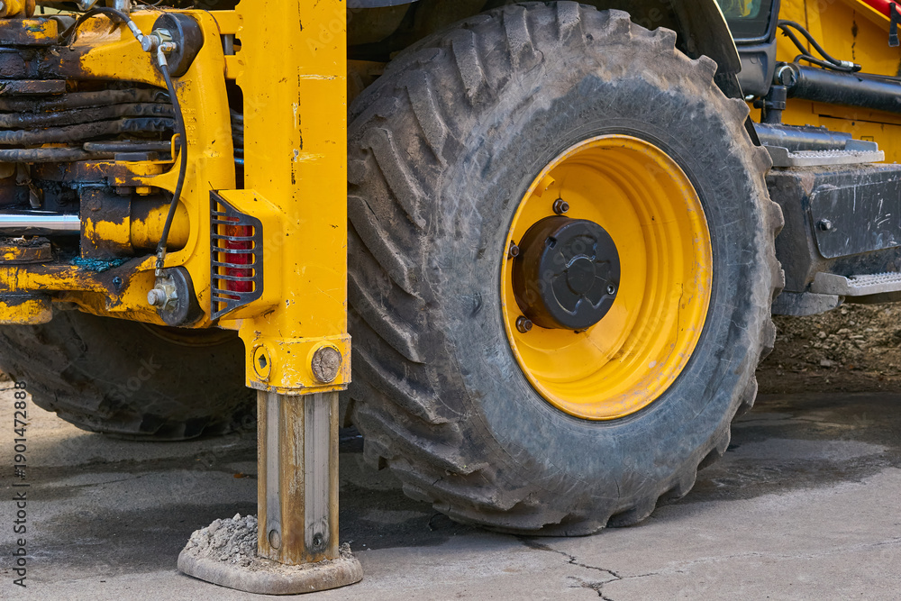 Fototapeta premium Lifting machine truck crane stands on stops,large wheel of tractor