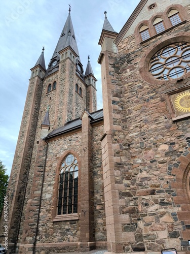 Mariestad, Sweden - August 28th 2024: View of the Mariestad Cathedral, a historic stone cathedral with tall spires, arched windows and a clock tower under an overcast sky in Sweden