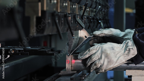 Precision metal bending with a hydraulic press. Close-up of a worker using a hydraulic press brake to bend a metal sheet, showcasing precision manufacturing and industrial safety.
