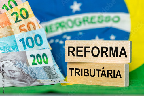 Tax reform, words written in Brazilian Portuguese on wooden blocks against the backdrop of the Brazilian flag and money. Financial Concept, Taxes in Brazil