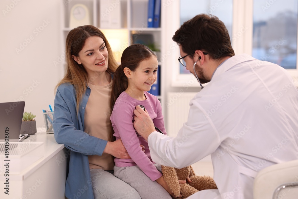 Fototapeta premium Little girl and her mother having appointment with pediatrician in hospital. Doctor checking child with stethoscope