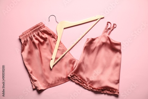 Принти на полотні Trendy silky pajamas and hanger on pink background, flat lay