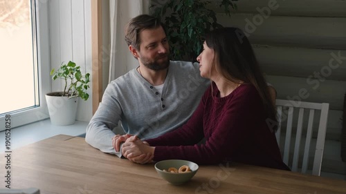 Loving mature couple interactions at home. Husband and wife hugging, holding hands and drinking morning coffee together. Man and woman talk about plans for weekend. Natural lighting. Intimate moments.