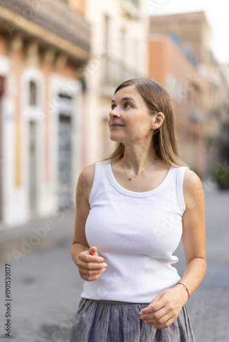 Long-haired brunette woman walks along city street, spends time in motion, walks and enjoys sunny warm day. Man and city, walk alone.. Free Download Long-haired brunette woman walks along city street, spends time in motion, walks and enjoys sunny warm day. Man and city, walk alone.. - GFXLoad