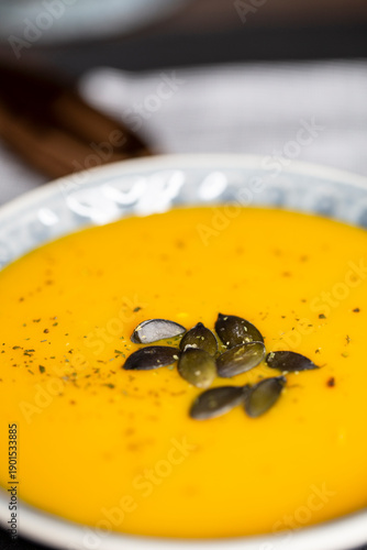 Kürbissuppe in einer Suppenschale auf einem gedeckten Tisch. Nahaufnahmeder Suppe.