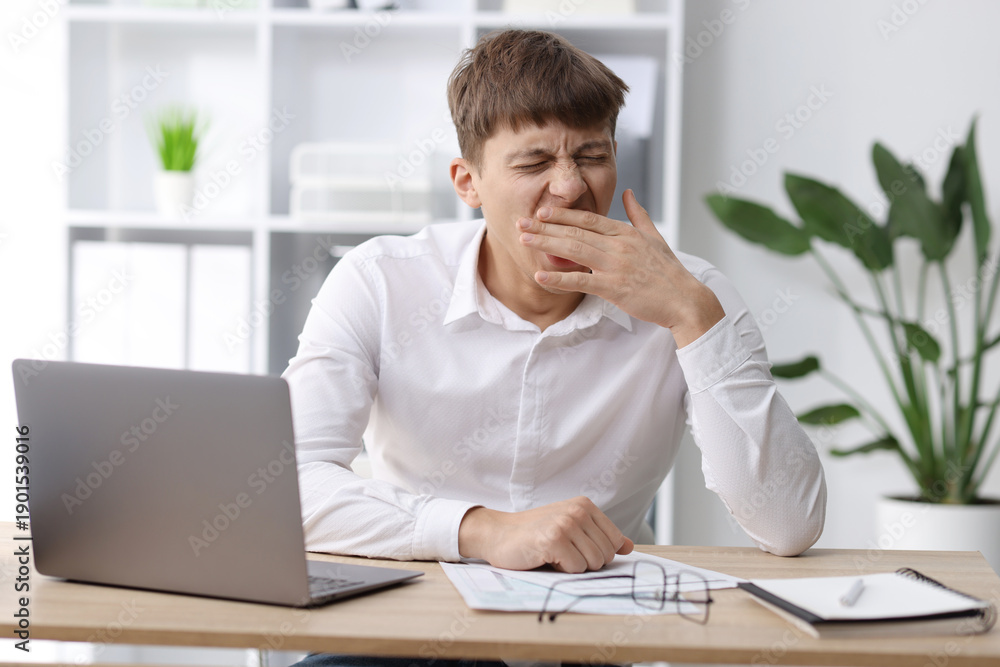 Naklejka premium Work fatigue. Overwhelmed businessman yawning at table in office