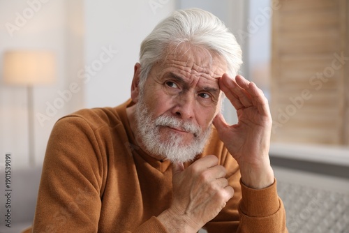 Photos Amnesia. Senior man trying to remember something at home