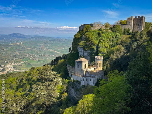 Obraz na plátně Stone fortress ruins perched on a lush cliff above a towered building and a wide Sicilian valley stretching into the distance