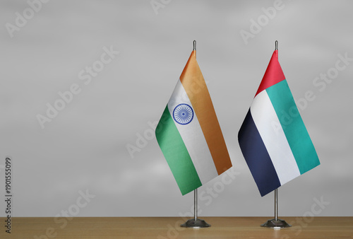 Two table flags of India and Emirates on a blurred gray background