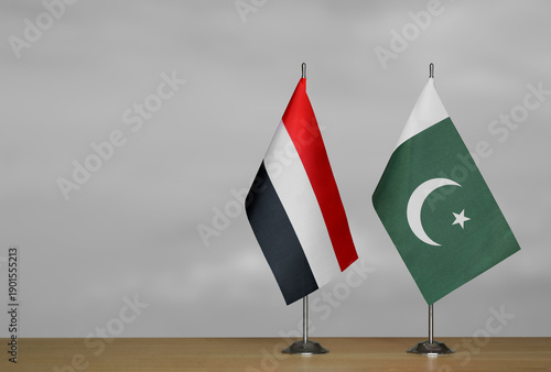 Two table flags of Yemen and Pakistan on a blurred gray background