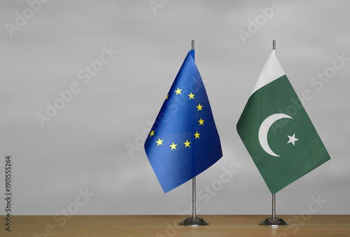 Two table flags of the European Union and Pakistan on a blurred gray background