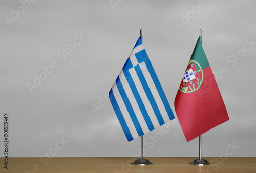 Two table flags of Greece and Portugal on a blurred gray background